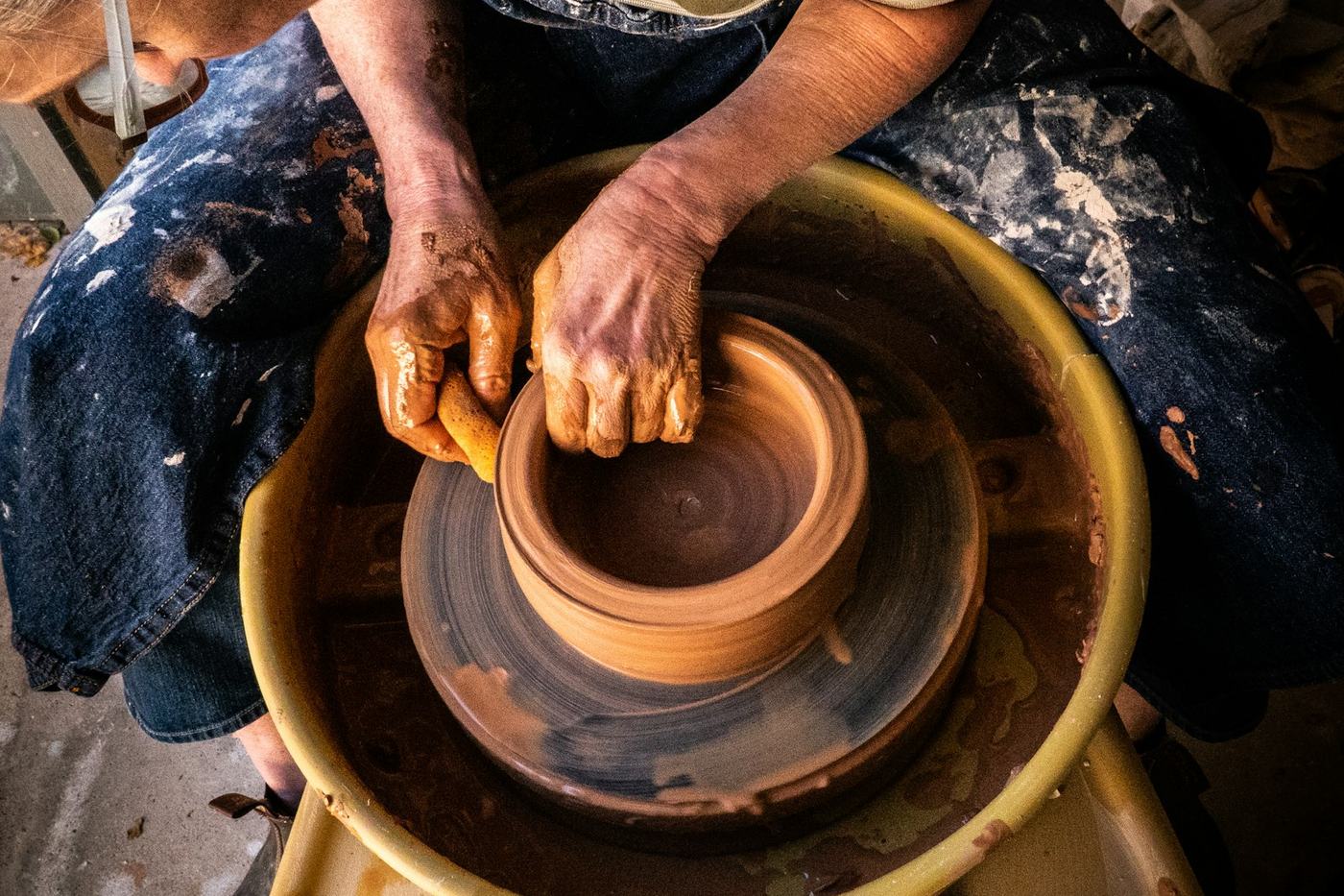 Hands shaping clay on a pottery wheel